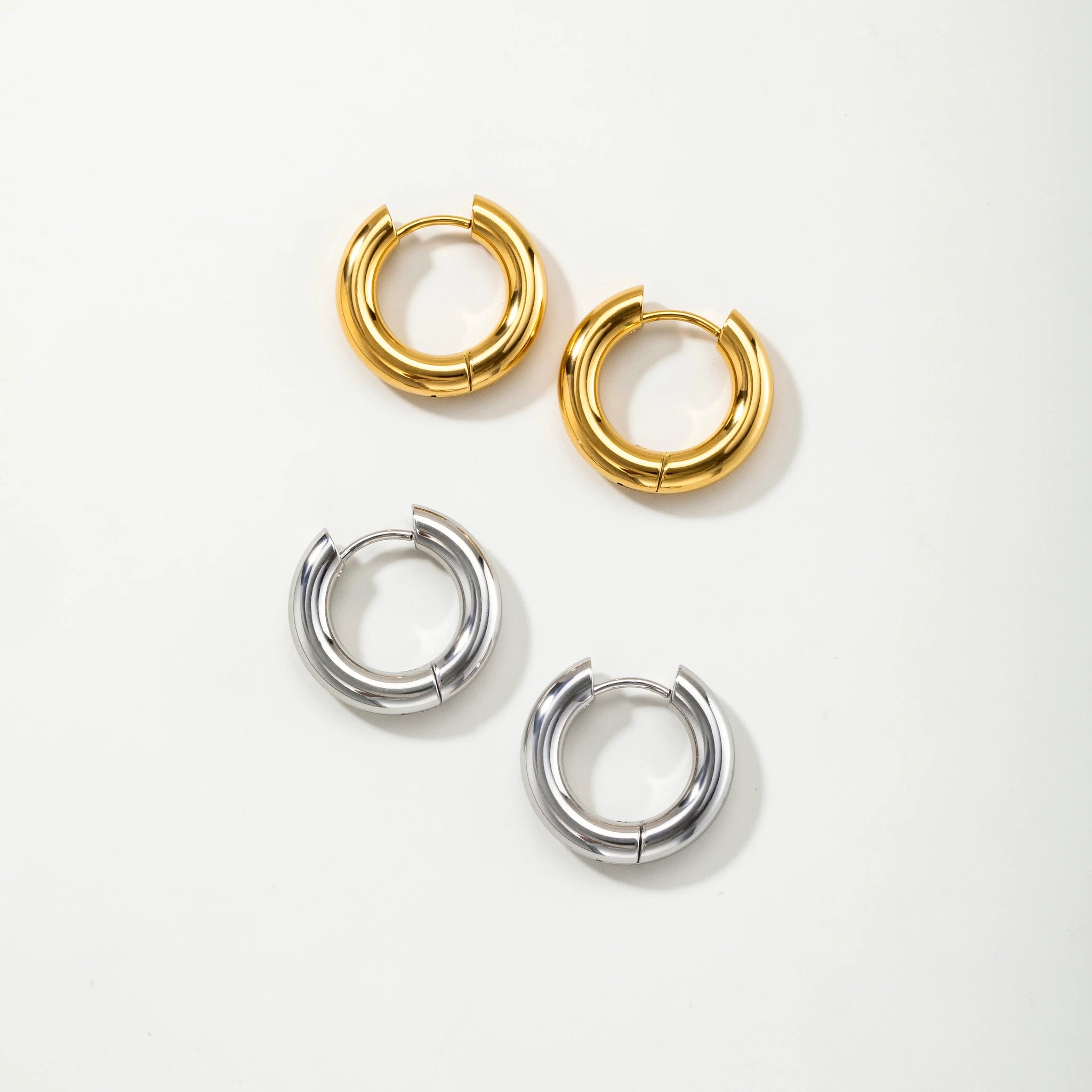 Four small hoop earrings on a plain white background: two gold-toned hoops at the top and two silver-toned hoops at the bottom.