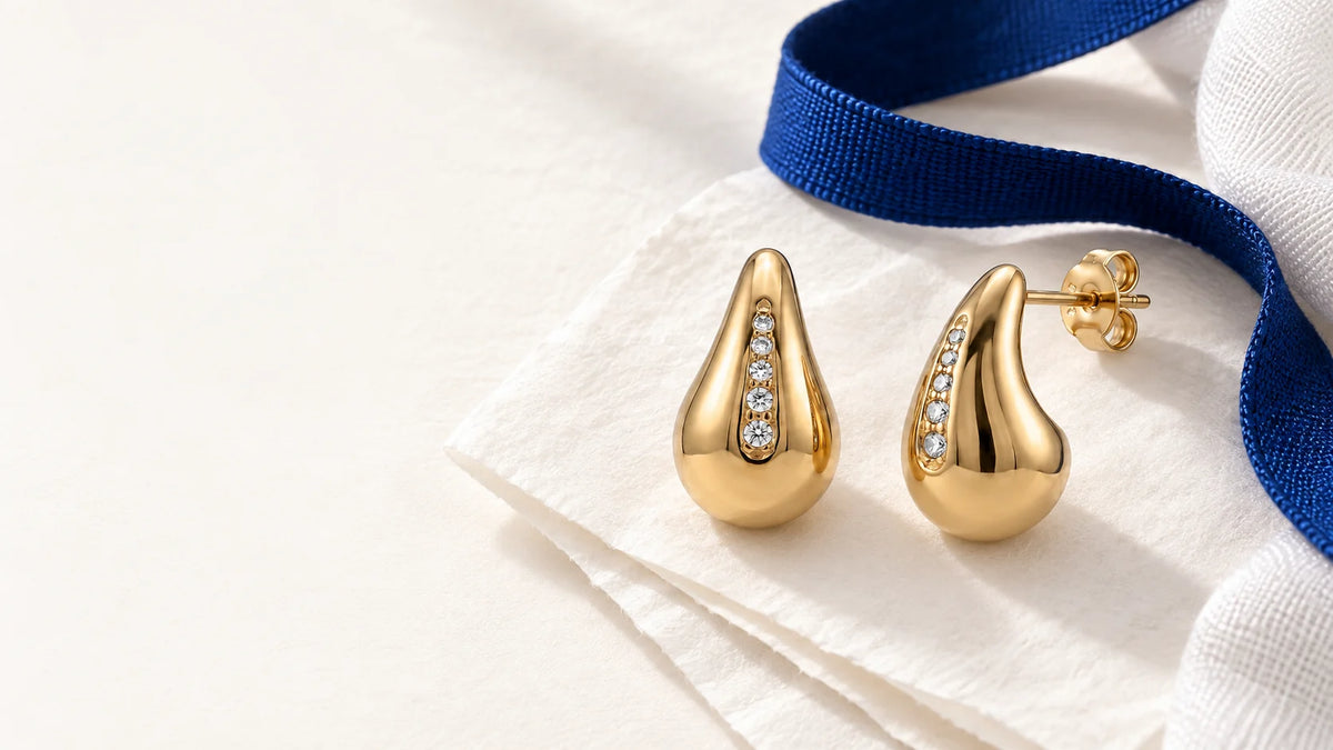 Mara teardrop earrings on tissue paper beside a blue ribbon
